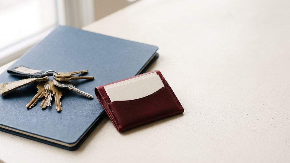 Shop keys on a blue folder next to a red holder of blank business cards